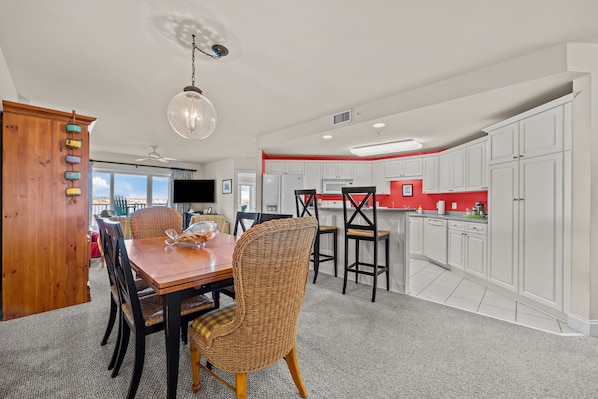 A dining area with a wooden table and wicker chairs, a ceiling fan, and a view of the city.