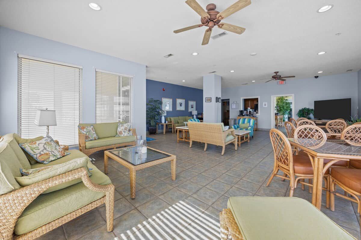 A spacious living area with wicker furniture, a ceiling fan, and a dining table with chairs.