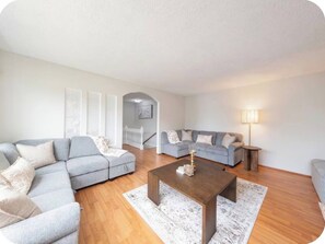 A living room with a sectional sofa, a smaller sofa, a coffee table, and a lamp. - Spacious 3BR/2BA Family Home in Delta | Sleeps 12 (Delta)