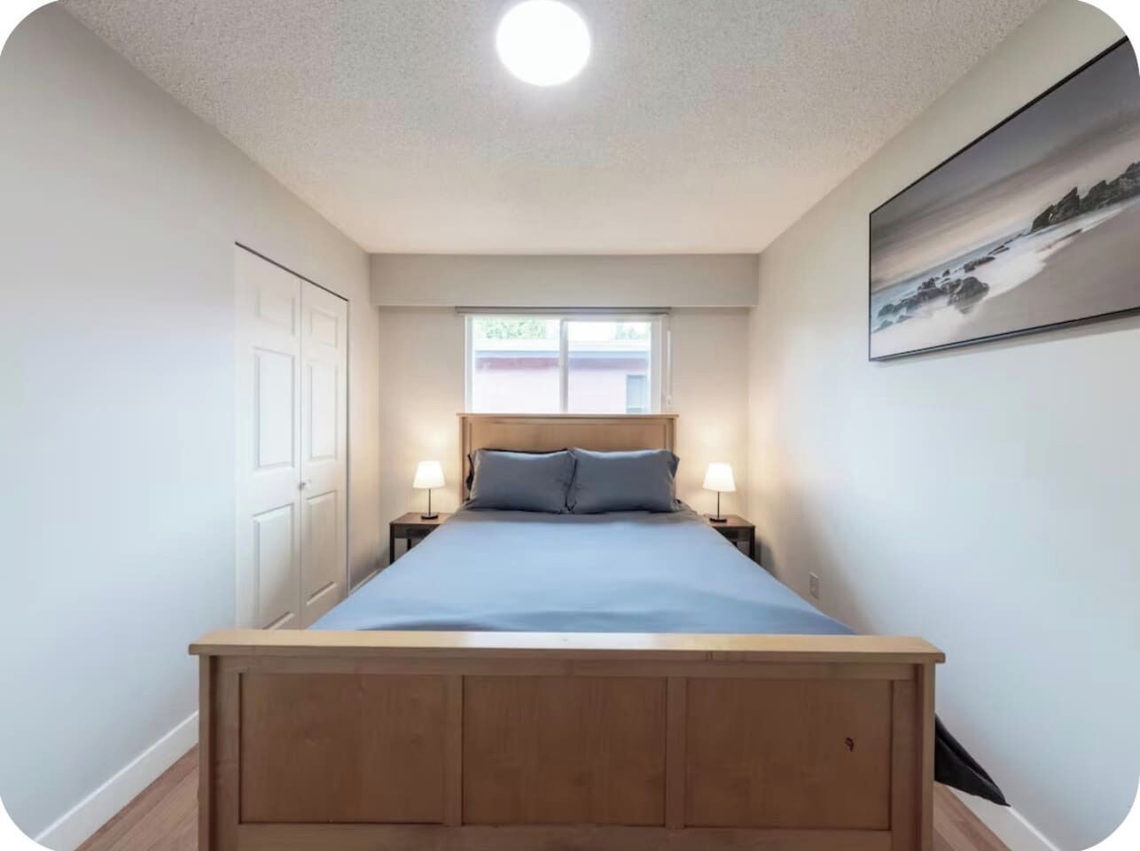 Ein Schlafzimmer mit einem hölzernen Bett, zwei Nachttischlampen, einem Fenster und einer Tür.