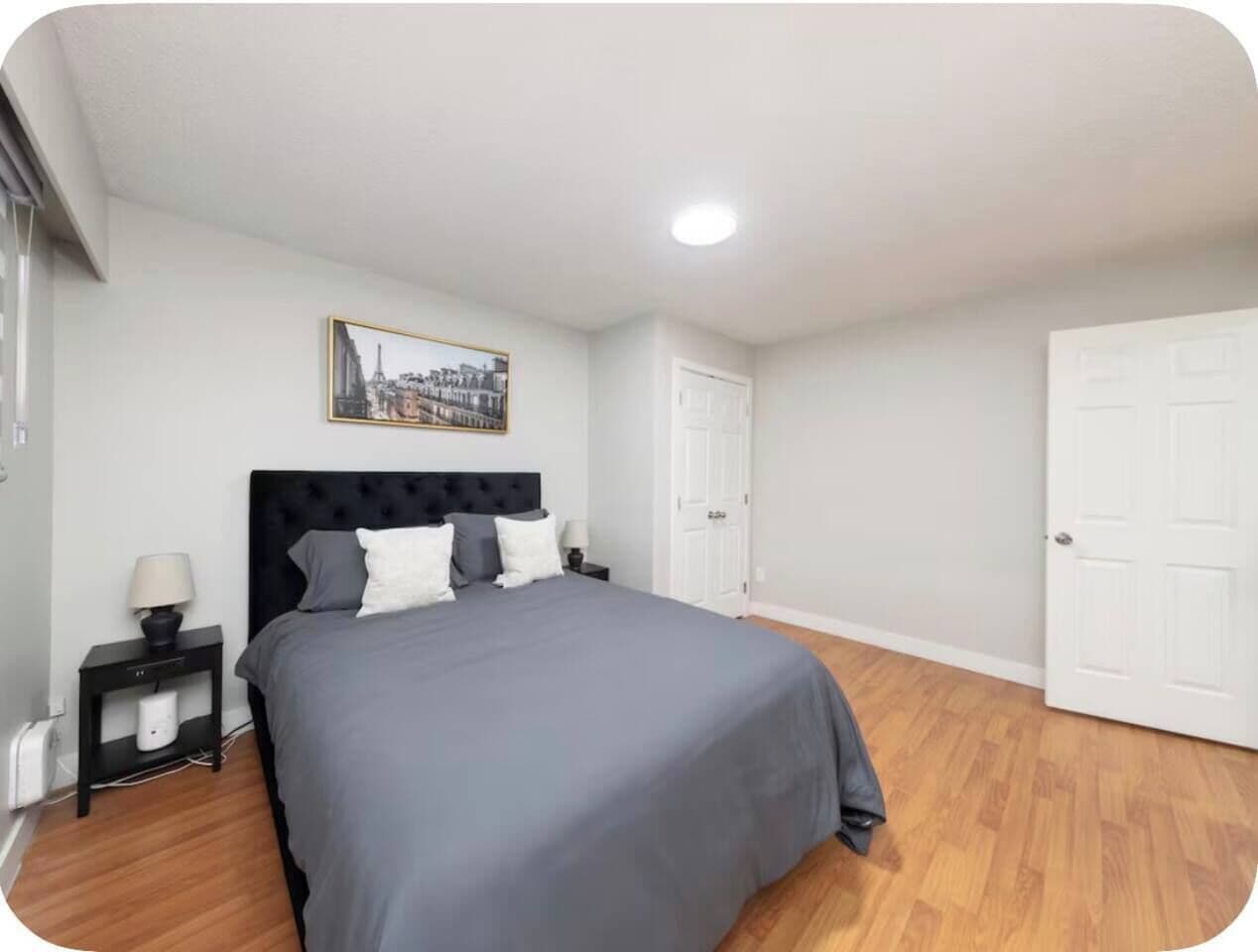 Ein Schlafzimmer mit Bett, Nachttischen, einem Wandbild und einer Tür.