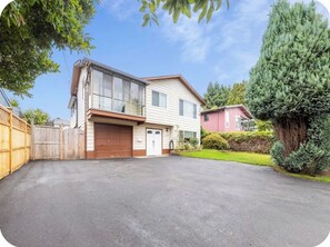 Ein zweistöckiges Haus mit Garage, Auffahrt und gepflegtem Rasen.