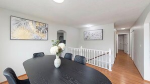 A dining area with a round table, chairs, and a vase of flowers. There are two framed artworks on the walls. - Spacious 3BR/2BA Family Home in Delta | Sleeps 12 (Delta)