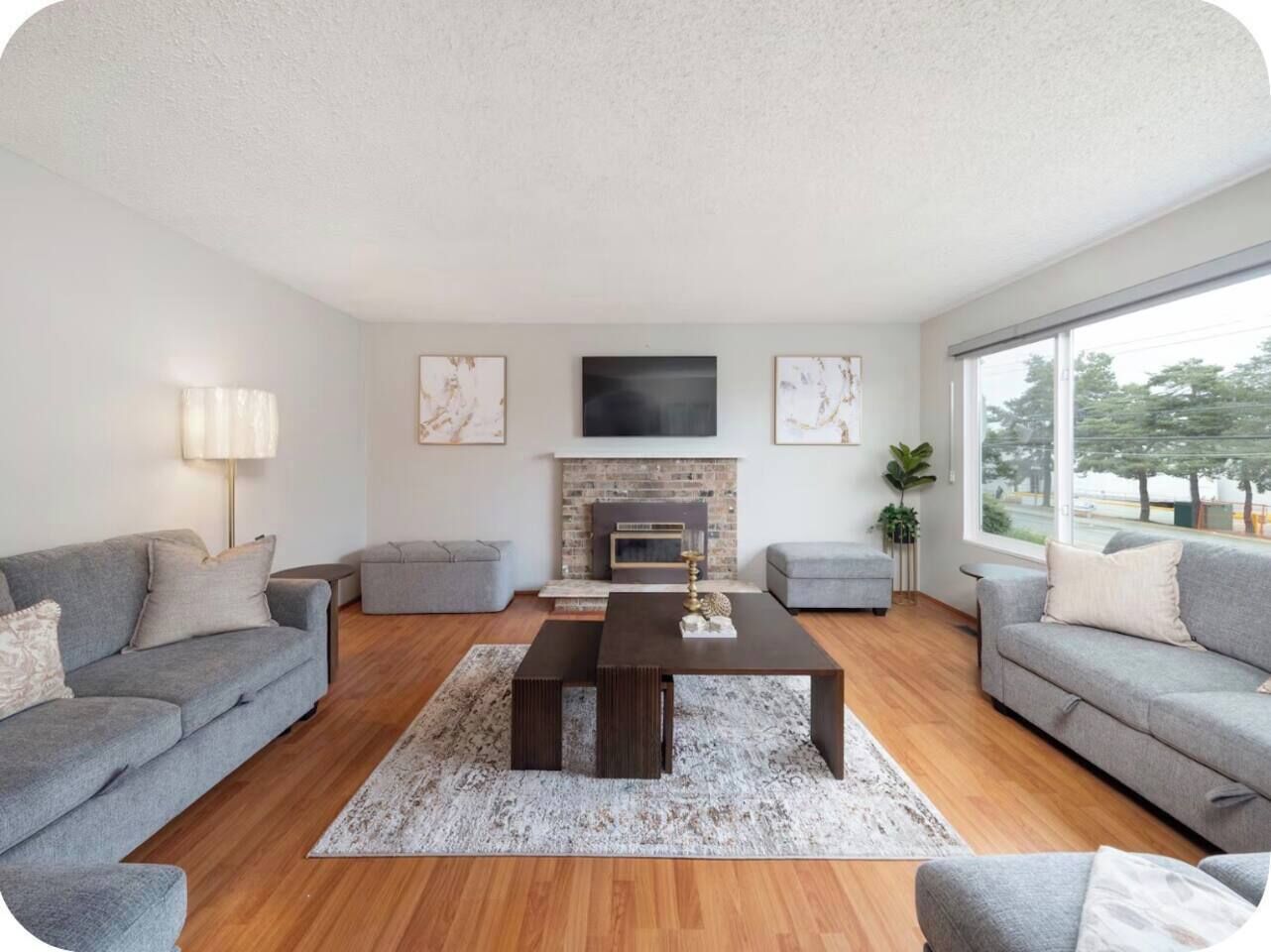 A modern living room with a fireplace, grey sofas, a coffee table, and artwork on the walls.