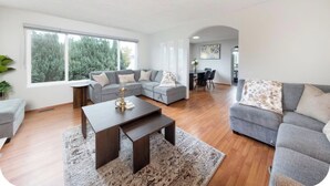 A modern living room with a sectional sofa, a coffee table, and a dining area with chairs. - Spacious 3BR/2BA Family Home in Delta | Sleeps 12 (Delta)