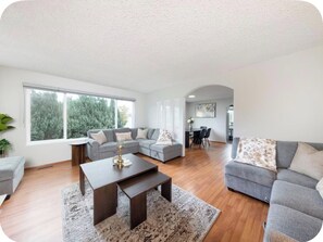 A modern living room with a sectional sofa, a coffee table, and a dining area with chairs.
