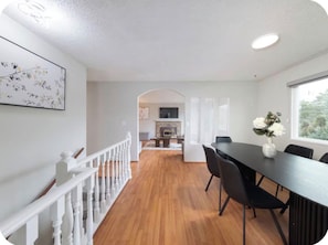 Un intérieur moderne comprenant un coin repas, un escalier et une cheminée.