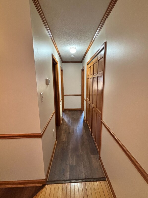 A narrow hallway with wooden paneling on the walls and a wooden floor.
