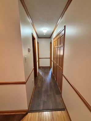 A narrow hallway with wooden paneling on the walls and a wooden floor.