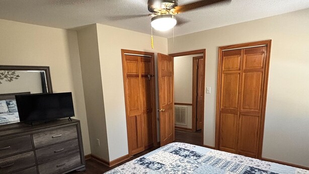 A bedroom with a bed, dresser, and a ceiling fan.