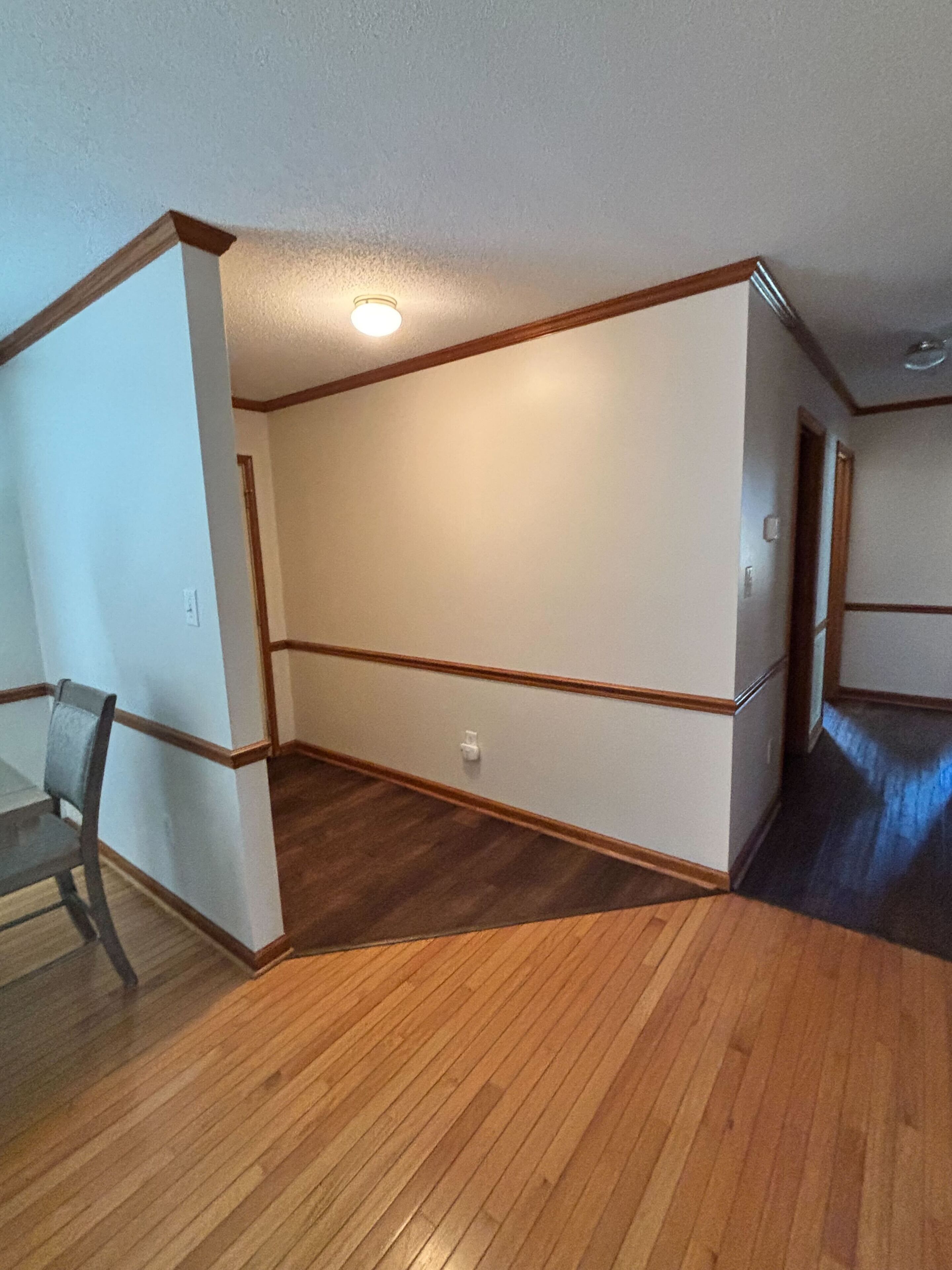 A room with a wooden floor, white walls, and a ceiling light.