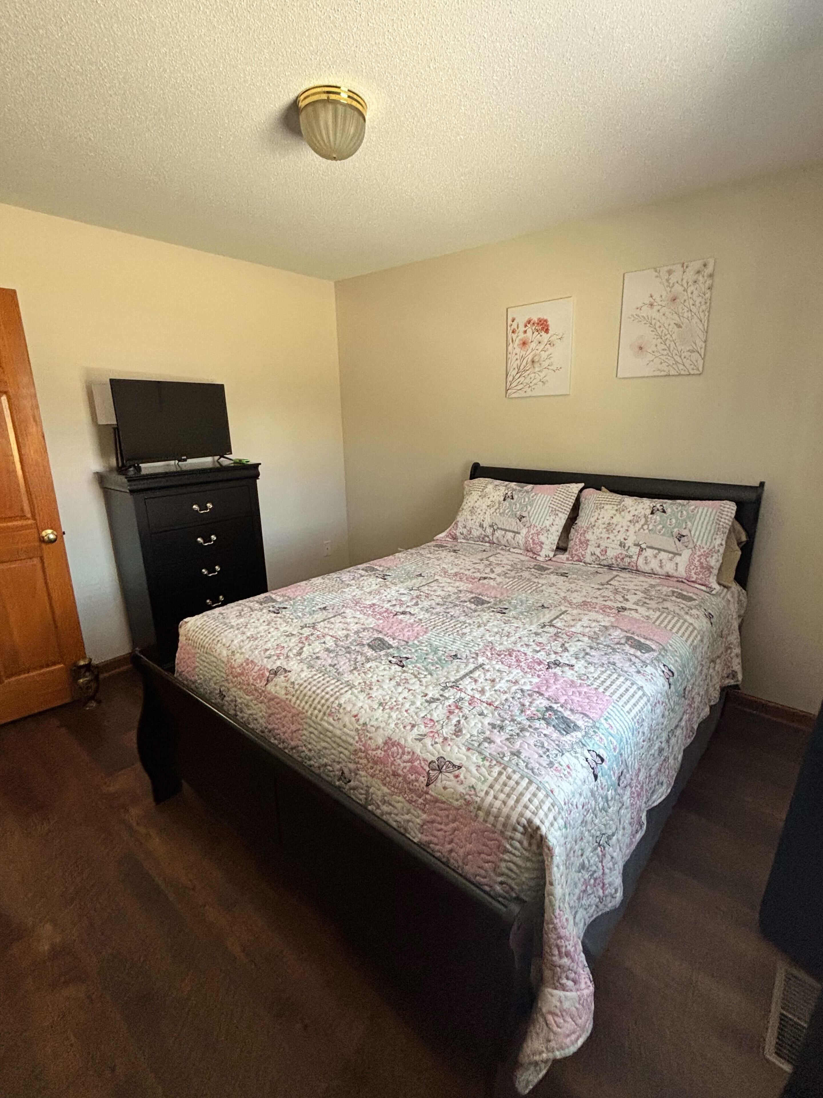 Une chambre à coucher avec un lit, une commode et un téléviseur posé sur le dessus.