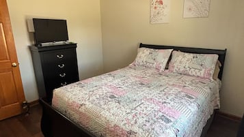 Une chambre à coucher avec un lit, une commode et un téléviseur posé sur le dessus.