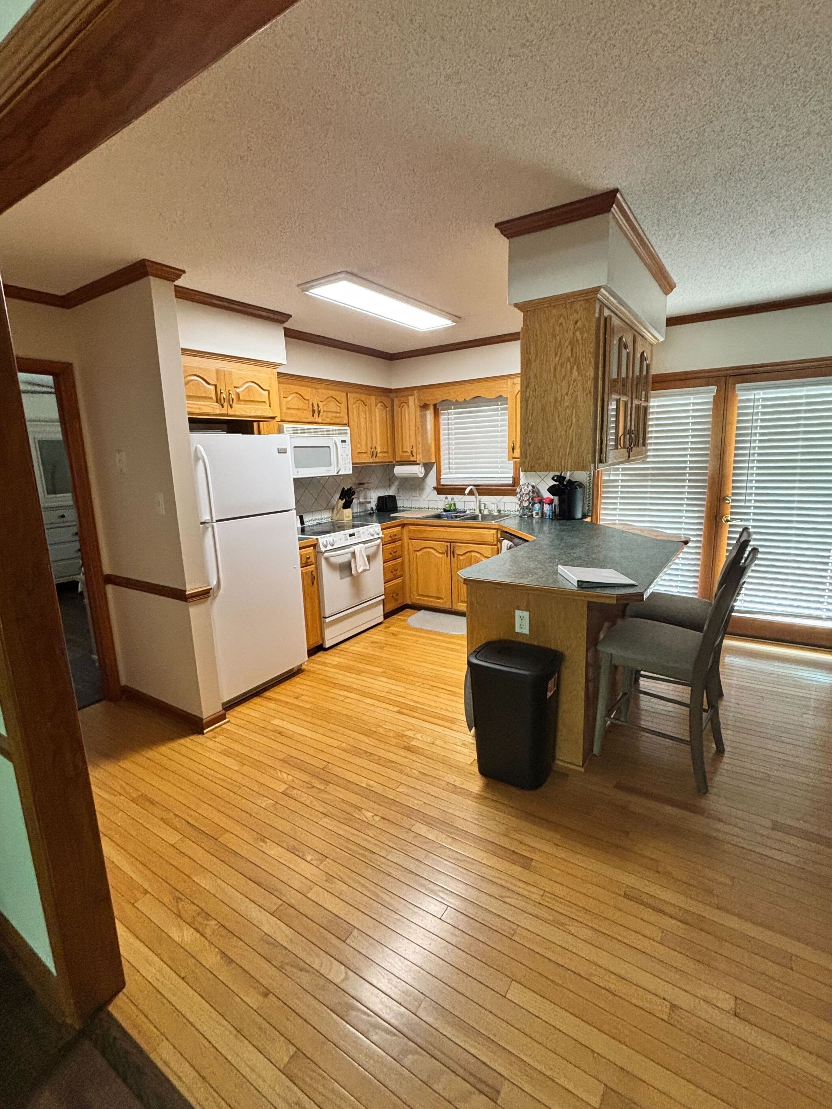 A kitchen with wooden cabinets, a refrigerator, a microwave, and a sink.