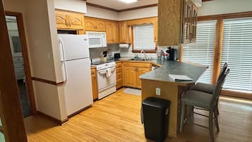 A kitchen with wooden cabinets, a refrigerator, a microwave, and a sink.