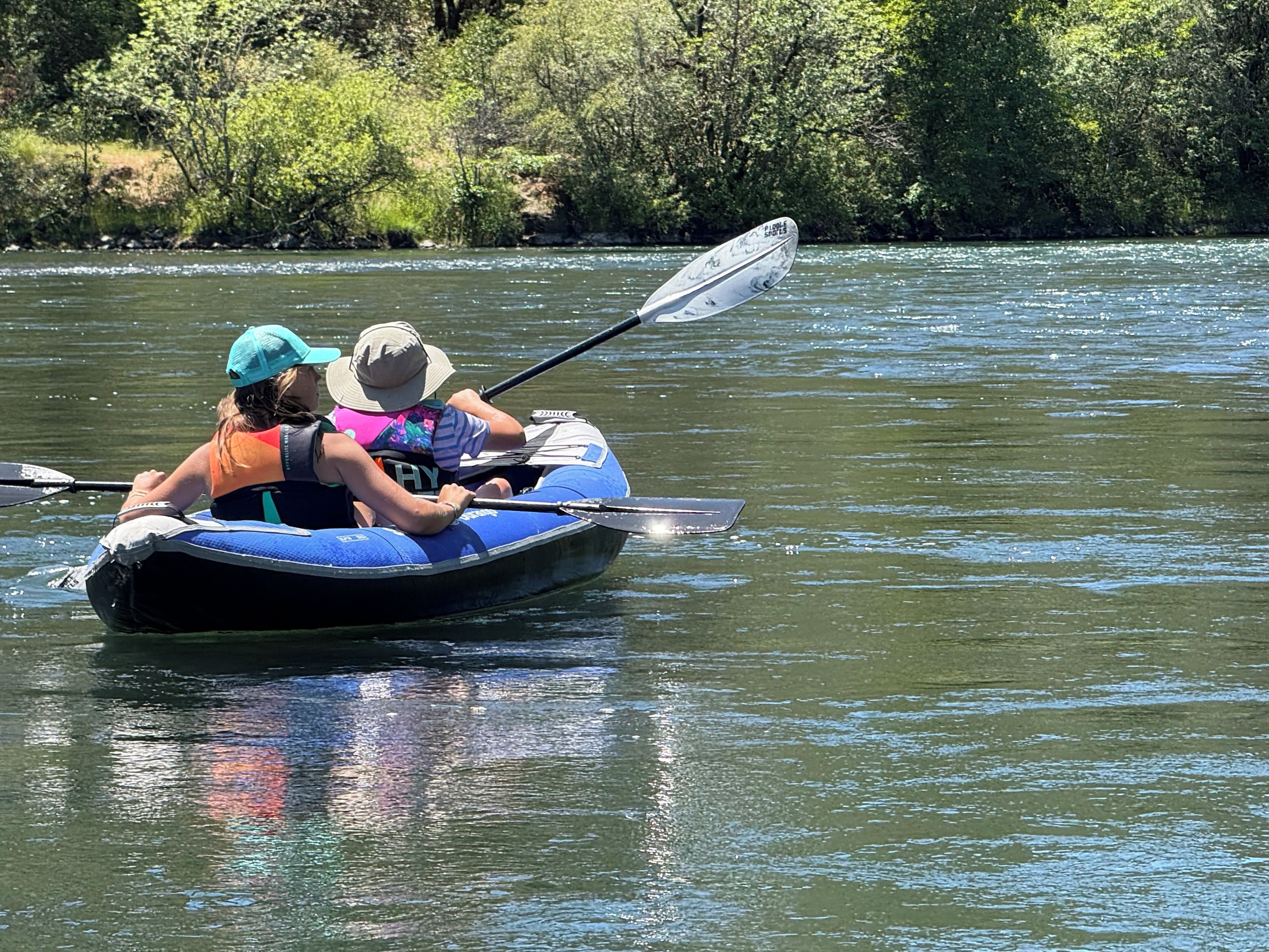 A person in a blue inflatable boat on a river.