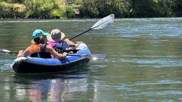 A person in a blue inflatable boat on a river.