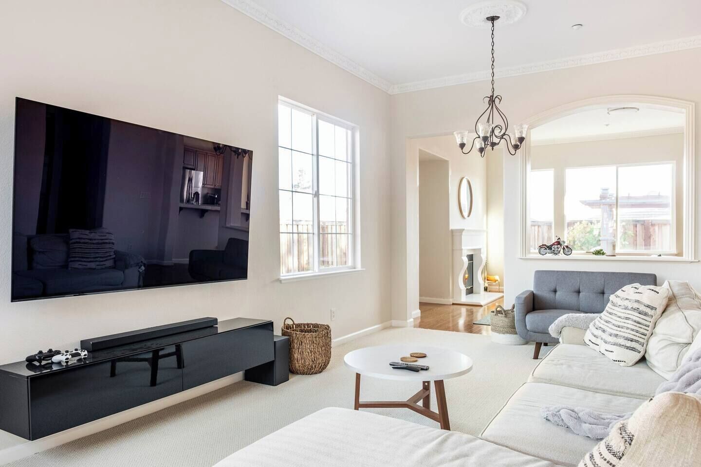 Een moderne woonkamer met een flatscreen televisie, een bank, een salontafel en een open haard op de achtergrond.