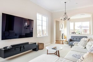 A modern living room with a flat-screen TV, a sofa, a coffee table, and a fireplace in the background. - Spacious 4-Bedroom Single-Story Home in Brentwood (Brentwood)