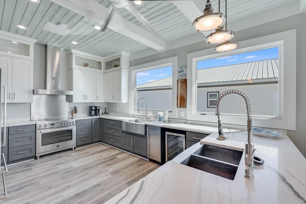 A modern kitchen with a stainless steel range, a double sink, and a large window providing natural light.