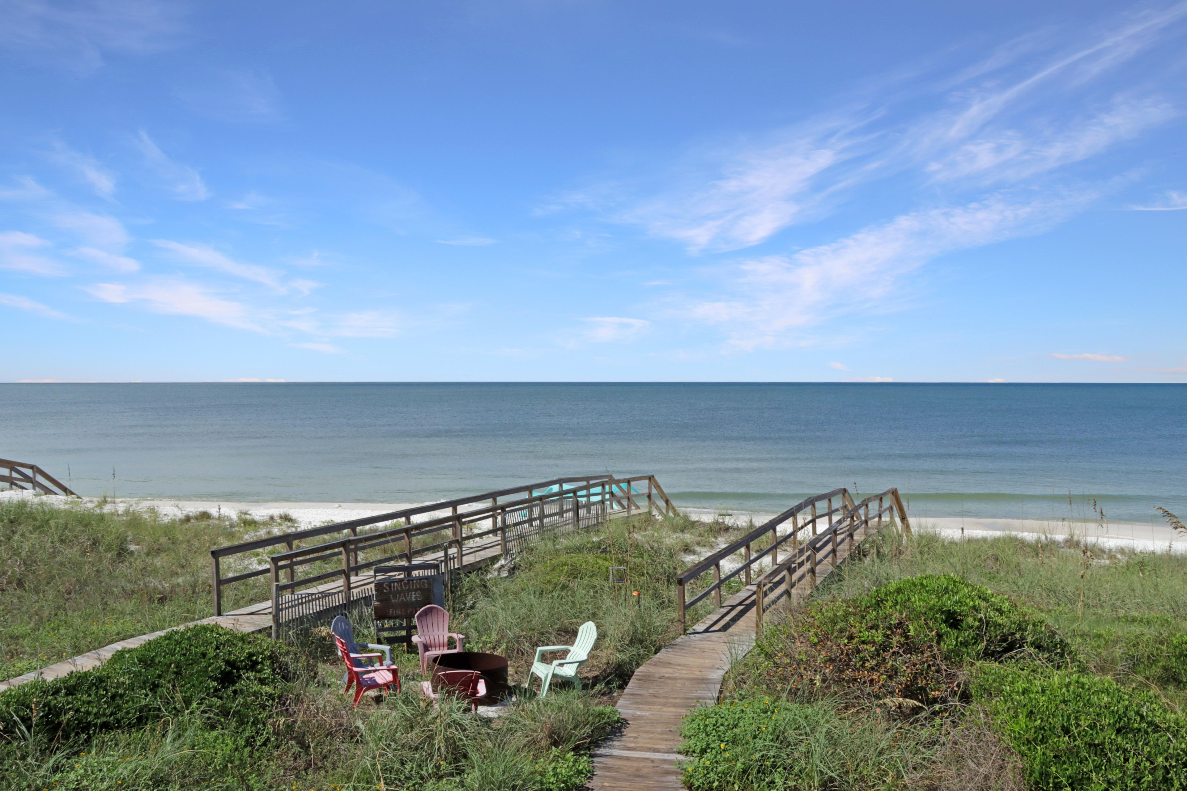 A wooden boardwalk leading to beach chairs and a sign indicating a swimming area.