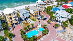 A coastal residential area with multiple two-story houses, a central swimming pool, and a beach in the background. - Singing Waves (Port St. Joe)