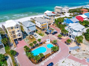 A coastal residential area with multiple two-story houses, a central swimming pool, and a beach in the background. - Singing Waves (Port St. Joe)