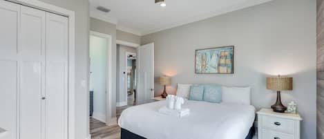 A bedroom with a bed, a ceiling fan, a nightstand with a lamp, and a painting on the wall.