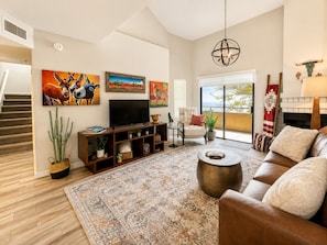 A living room with a sofa, a coffee table, a TV, and artwork on the wall. - Modern Villa+ Scottsdale Resort + Pool + Golf Course+ Walking paths +Gym +Dining (Scottsdale)