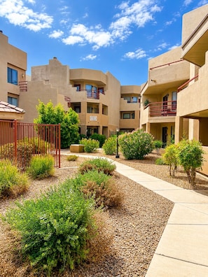A courtyard with a pathway, surrounded by low-rise buildings with balconies, and various shrubs and plants. - Modern Villa+ Scottsdale Resort + Pool + Golf Course+ Walking paths +Gym +Dining (Scottsdale)