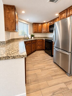 A kitchen with wooden cabinets, a stainless steel refrigerator, and a granite countertop. - Modern Villa+ Scottsdale Resort + Pool + Golf Course+ Walking paths +Gym +Dining (Scottsdale)