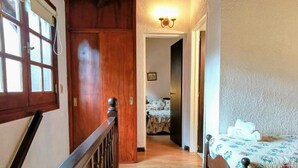 Quarto com cama de madeira, mesa de cabeceira e janela com cortinas.