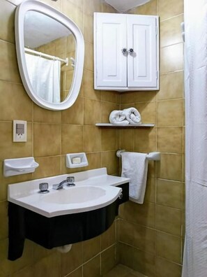 Un baño con un lavamanos blanco, un espejo, un perchero y un armario.