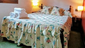 A neatly made bed with floral bedding and a stack of folded towels. - Apart Rose Garden (San Martin de los Andes)