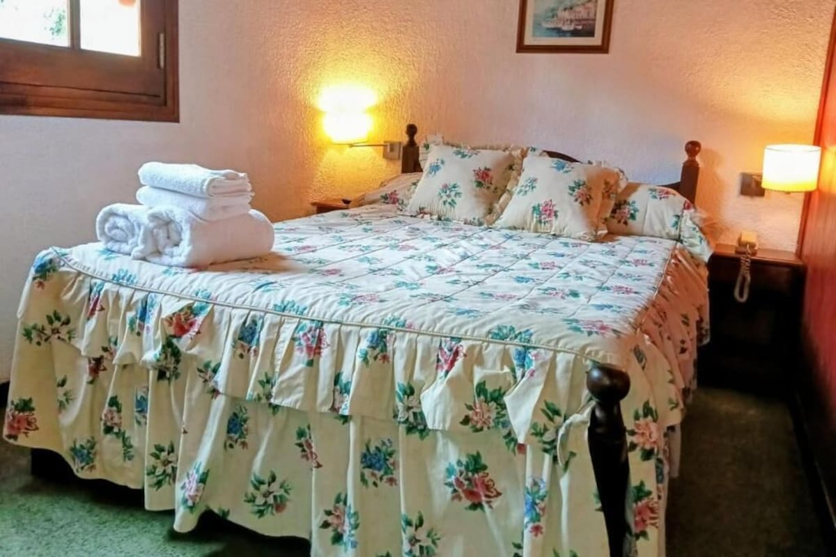 Una cama bien hecha con ropa de cama floral y una pila de toallas dobladas.