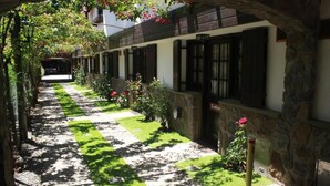 Um corredor com piso xadrez, paredes de pedra e uma fileira de janelas com persianas.