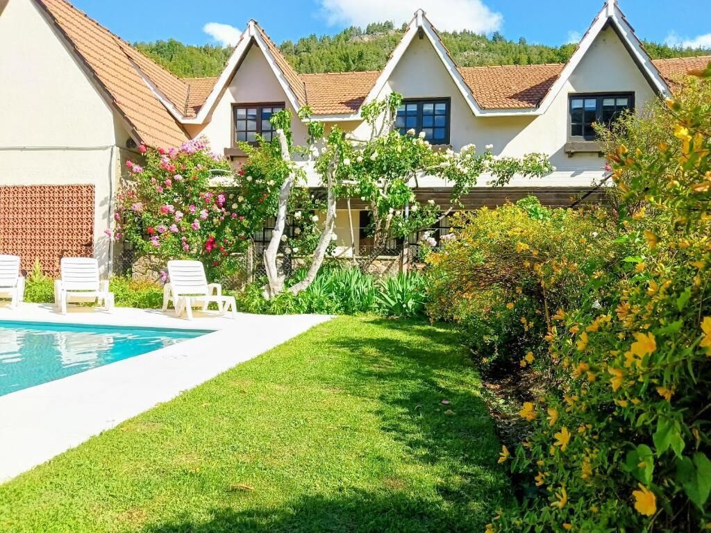 A row of white cottages with pitched roofs, a swimming pool, and a well-maintained lawn.