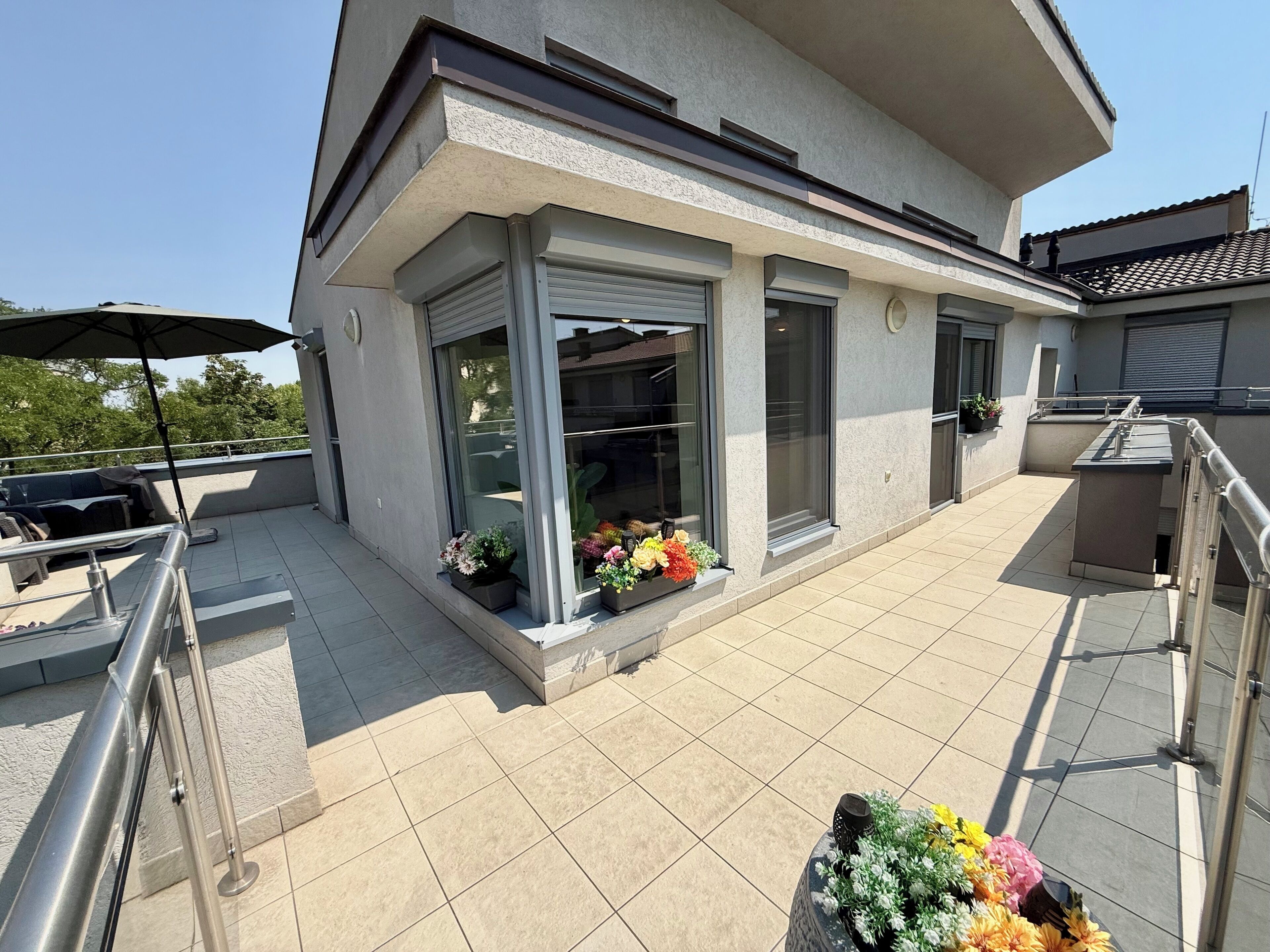 Un bâtiment moderne doté d’un balcon, d’un espace extérieur aménagé et de plantes en pot.