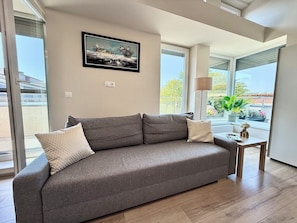 A modern living room with a grey sofa, a small table, and a framed picture on the wall.