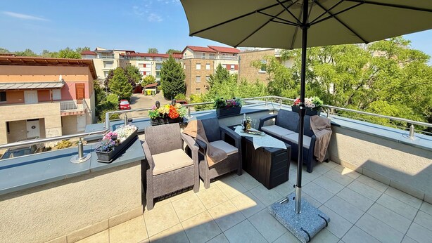 A rooftop terrace with outdoor furniture, a large umbrella, and potted plants. - Penthouse with a Panorama balcony, and free Parking! (Kecskemét)
