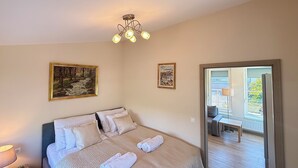 A bedroom with a bed, two paintings, a ceiling light fixture, and a view of an outdoor balcony. - Penthouse with a Panorama balcony, and free Parking! (Kecskemét)