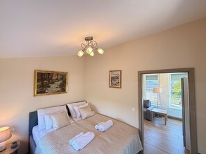 A bedroom with a bed, two paintings, a ceiling light fixture, and a view of an outdoor balcony. - Penthouse with a Panorama balcony, and free Parking! (Kecskemét)