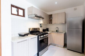 Eine moderne Küche mit einem Edelstahlkühlschrank, einem Gasherd und Holzschränken.