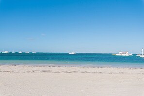 Ein Strand mit klarem, blauem Wasser und mehreren Booten.