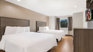 A hotel room with two beds, a TV, and a window with curtains.