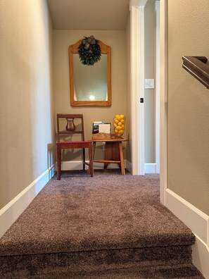 A carpeted stairway leading to a room with a mirror, a chair, and a table with a vase of lemons. - A Room in a Lake and Mountain Town (Coeur d'Alene)