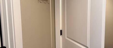 Una puerta blanca cerrada con un picaporte negro y un perchero de madera con ganchos en la pared.