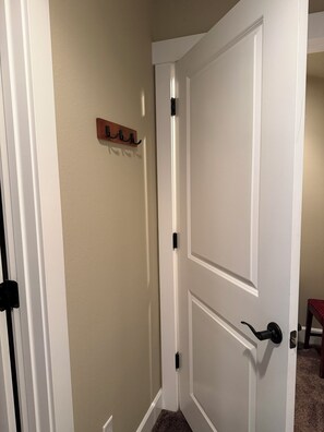 A closed white door with a black handle and a wooden coat rack with hooks on the wall. - A Room in a Lake and Mountain Town (Coeur d'Alene)