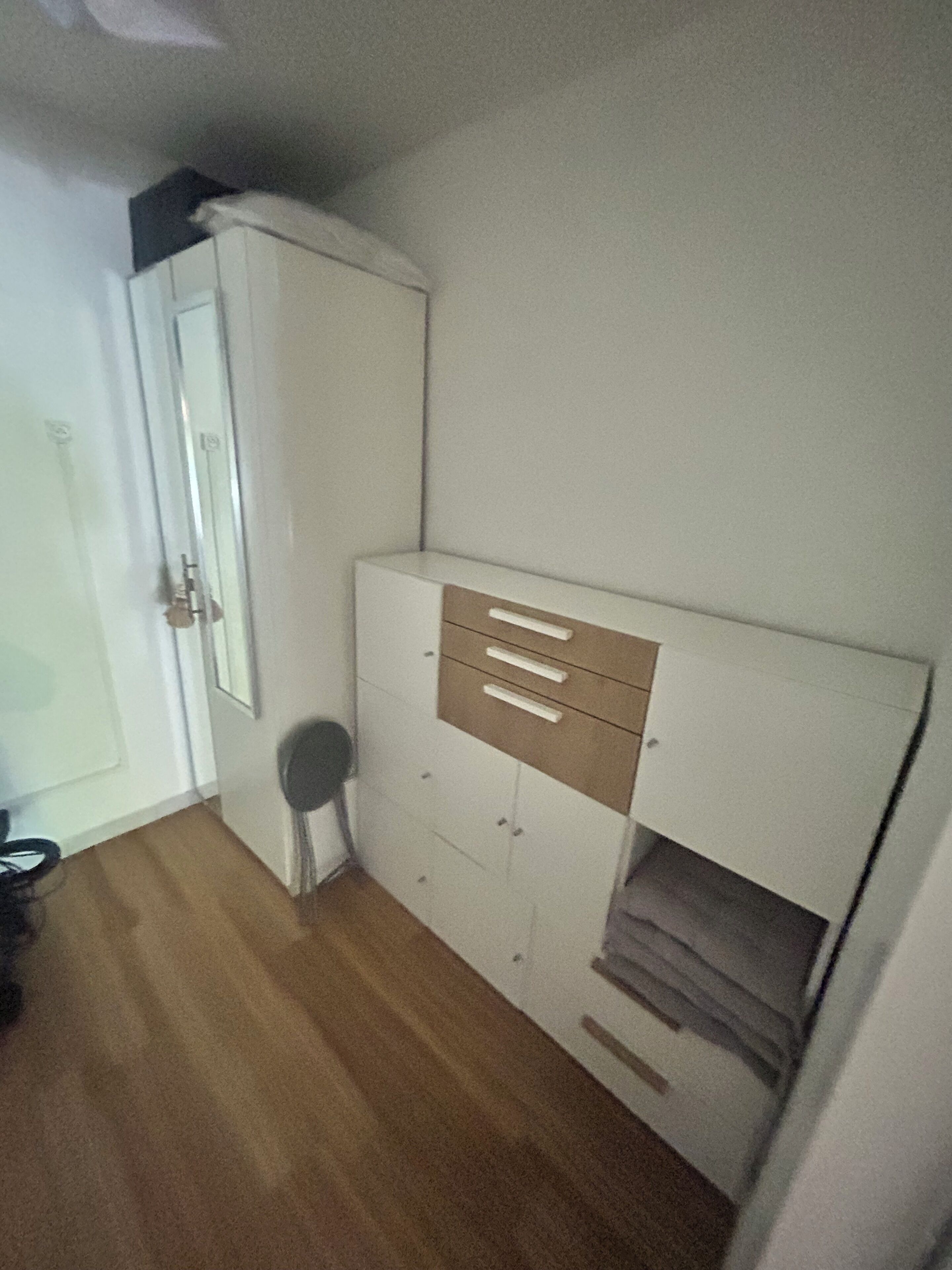 A room with a bed, a wardrobe, and a chair.