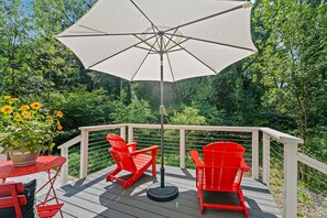 A wooden deck with two red chairs and a large umbrella. - Timber & Tide: Two-Space Woodland Retreat (Saugatuck)